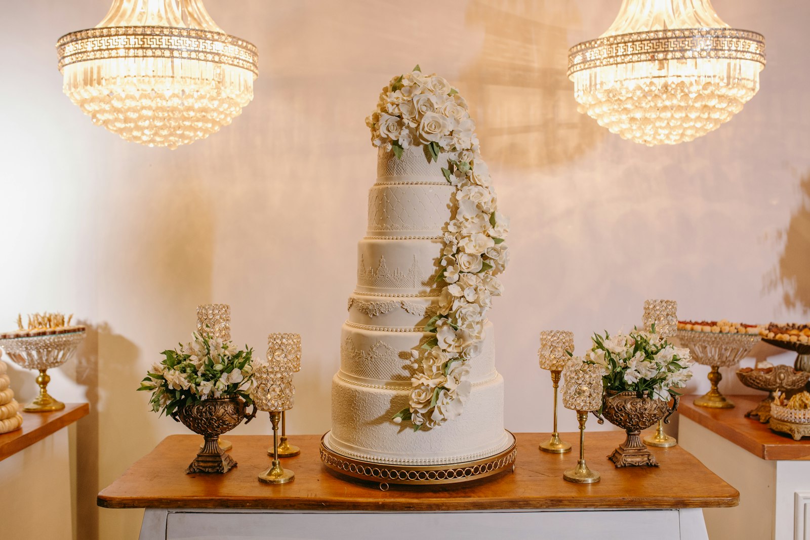 Torta de matrimonio de varios pisos bajo lámparas de cristal